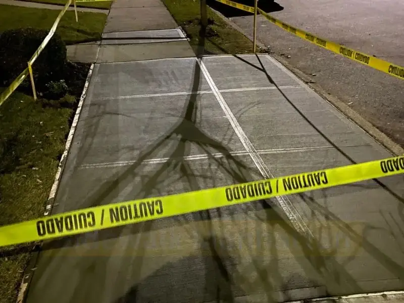 New concrete sidewalk flags with fresh control joints, protected by caution tape