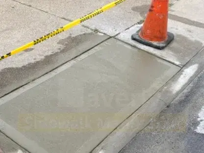 Replaced concrete sidewalk flag beside a curb, taped off with a traffic cone while it cures